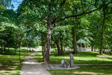 Stone pathway in the green park with white pavilion and street lighting. Park of Saka manor. Estonia. Baltic.