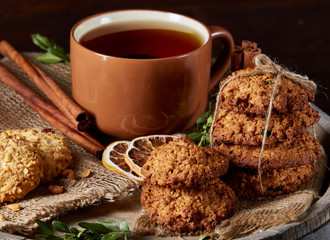 Traditional Christmas tea concept with a cup of hot tea, cookies and decorations on a wooden background, selective focus
