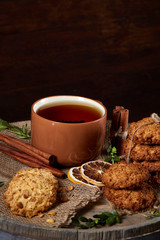 Traditional Christmas tea concept with a cup of hot tea, cookies and decorations on a wooden background, selective focus