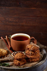 Traditional Christmas tea concept with a cup of hot tea, cookies and decorations on a wooden background, selective focus