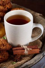 Traditional Christmas tea concept with a cup of hot tea, cookies and decorations on a wooden background, selective focus