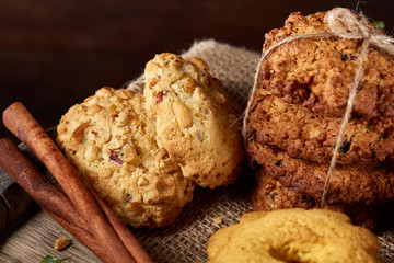 Conceptual composition with assortment of cookies and cinnamon on a wooden barrel, selective focus, close-up