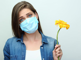 Woman wearing medical mask holding flower.