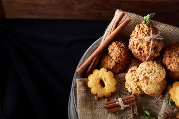Conceptual composition with assortment of cookies and cinnamon on a wooden barrel, selective focus, close-up