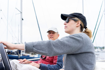 Daughter driving a motor cruiser out to sea with her father