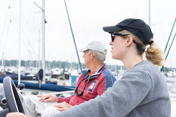 Daughter driving a motor cruiser out to sea with her father