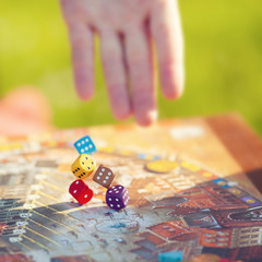 Close up: man hand throws dices on the table with Board game.