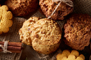 Conceptual composition with assortment of cookies and cinnamon on a wooden barrel, selective focus, close-up