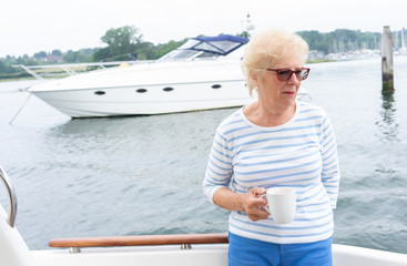 older woman having coffee on the back of a motor cruiser