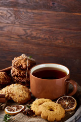 Traditional Christmas tea concept with a cup of hot tea, cookies and decorations on a wooden background, selective focus