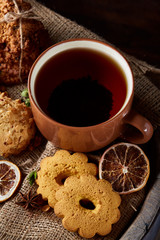 Traditional Christmas tea concept with a cup of hot tea, cookies and decorations on a wooden background, selective focus
