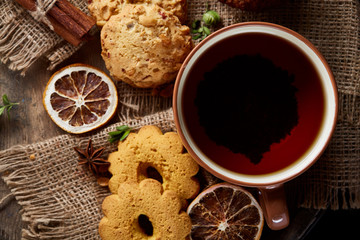 Traditional Christmas tea concept with a cup of hot tea, cookies and decorations on a wooden background, selective focus