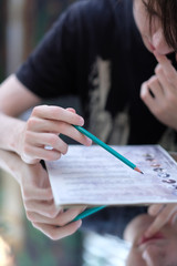 Portrait of a pensive teenager sitting at a mirror table with a pencil in his hands