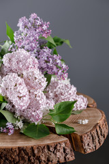 Lilac on a beautiful wooden table top from a saw. Fine flowers of gentle shades.