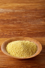 A wooden dish with millet on rustic wooden background, top view, close-up, selective focus.