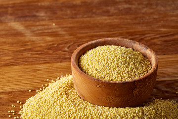 A wooden dish with millet on rustic wooden background, top view, close-up, selective focus.