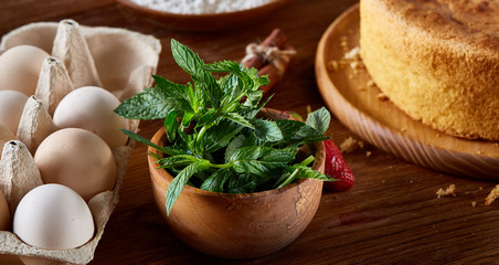 Fresh mint leaves in a bowl on wooden table, close-up, selective focus, shallow depth of field.