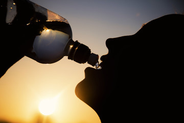 Silhouette of a woman drinking water at sunset