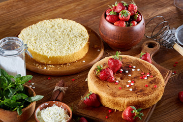 Delicious cake with fresh organic strawberries on cutting board over wooden background, close-up, selctive focus.