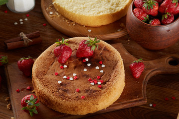 Delicious cake with fresh organic strawberries on cutting board over wooden background, close-up, selctive focus.