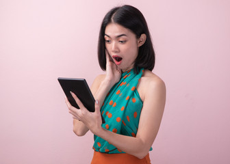 Asian teen looking at smartphone and feeling wow with shock deal in app isolated on pink background.