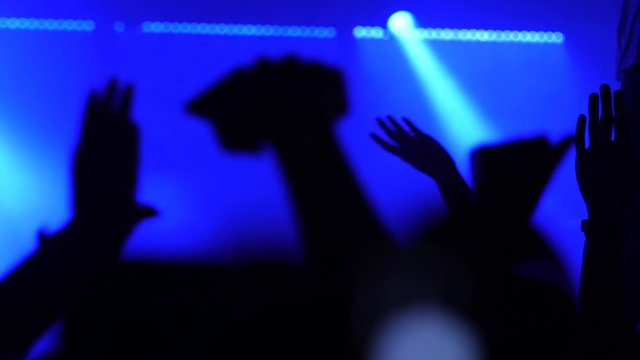 Dancing people silhouettes slow motion in disco concert stage lights raise hands enjoying rhythm
