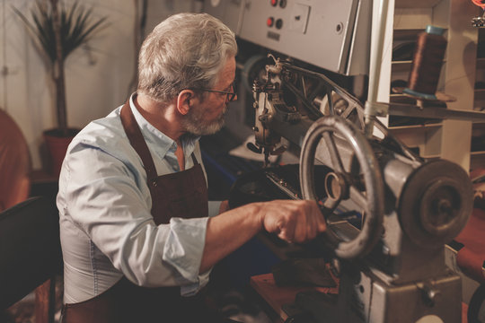 An elderly shoemaker in a workshop