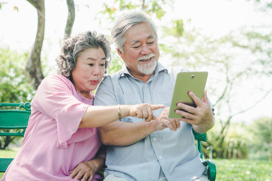 elderly people lifestyles and communication technology. Happy grandparent using tablet video call and talking with family in the park.