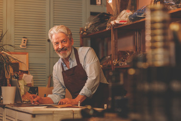 Smiling elderly shoemaker at the counter