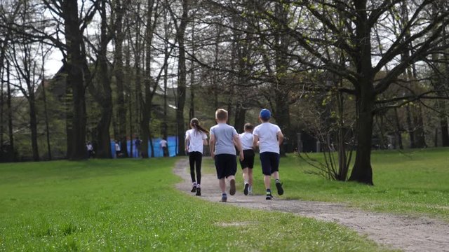 School age children run jogging during sport lesson in a green park in Wroclaw Poland