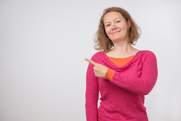 European woman swith smile showing product. Beautiful girl with curly hair pointing to the side