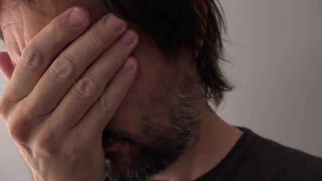 Sad man crying and covering face, close up of face