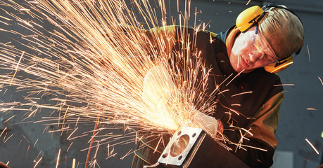 worker grinding weld seam with grinder machine and sparks - obrazy, fototapety, plakaty