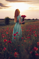woman standing in flowering poppy field, back to camera