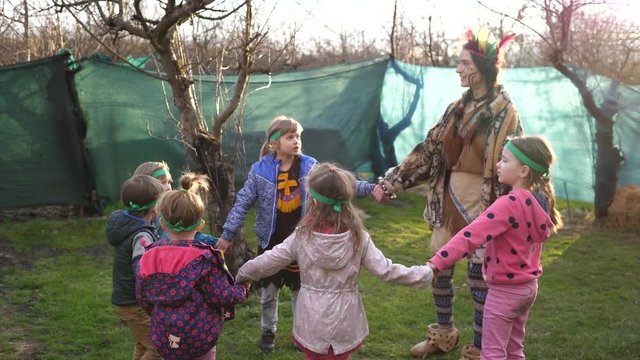 Animator woman play entertaining group of children on birthday theme party outdoors