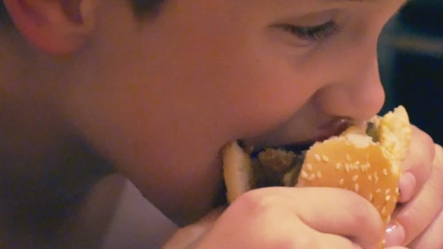 portrait of a hungry boy who eats a burger.