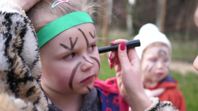 Body art painting animator paints face of little girl having fun and entertaining children on birthday party