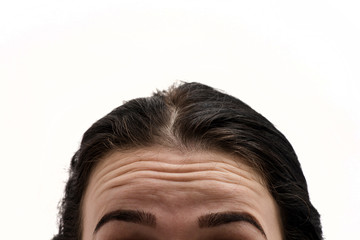 First wrinkles. Girl with wrinkles on forehead. Portrait of young woman with wrinkles on his forehead on white background. Do I have wrinkles? Woman looks in the mirror - 211262031