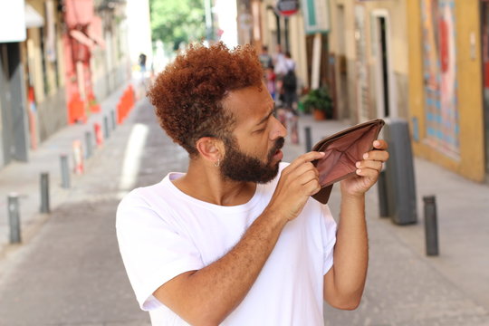 Ethnic broke guy with empty wallet outdoors