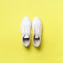 Stylish white sneakers and rope on yellow background with copy space. Top view. Minimal flat lay....