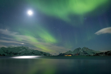 Fototapeta na wymiar Northern sea fjord in green aurora borealis lights and full moon