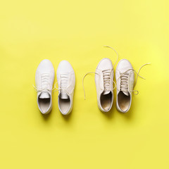 Old dirty sneakers vs new white sneakers on yellow background. Trendy footwear. Square crop. Top view. Concept of experience, discipline and chaos, accuracy \ mess, stylish shoes. Back to school