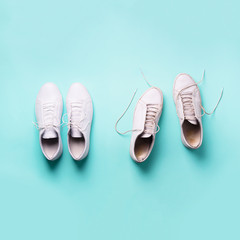 Old dirty sneakers vs new white sneakers on blue background. Trendy footwear. Square crop. Top...