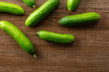Seven fresh mini cucumbers flatlay on brown wood background.