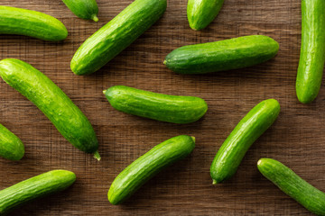 Fresh mini cucumbers flatlay on brown wood background.