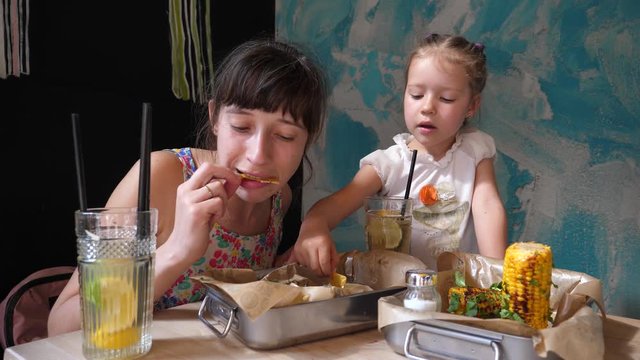 Young mother and child girl daughter eating nachos with sause in Mexican cuisine food restaurant
