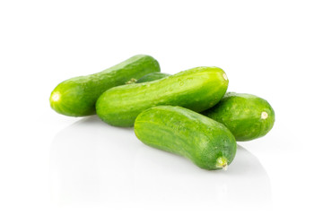 Four fresh green mini cucumbers isolated on white background.