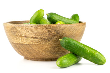 Fresh green mini cucumbers in a wooden bowl two cucumbers are near isolated on white background.