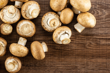 Fresh raw brown champignons table top on brown wood background.