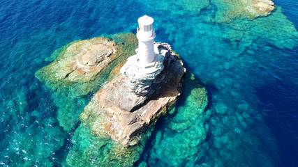 Aerial drone bird's eye view of iconic lighthouse of Tourlitis in port of Andros island chora,...